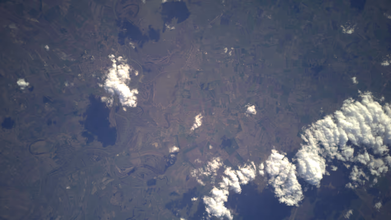 Aerial view of a landscape with scattered clouds casting shadows on the ground below.